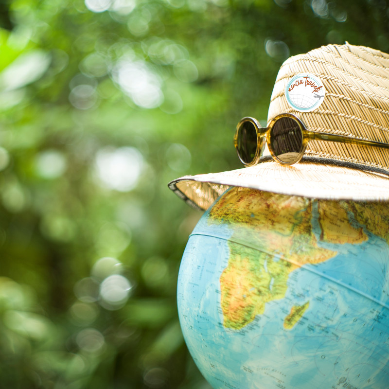 Un globo terráqueo con sombrero y gafas de sol entre la vegetación